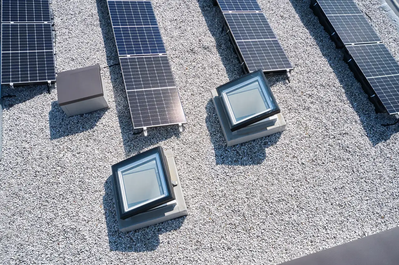 Détail d’un toit plat rénové avec des fenêtres pour toits plats VELUX et des panneaux solaires.