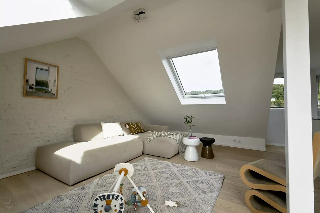 Canapé sous la fenêtre de toit dans un salon avec une pente de toit | Magazine VELUX